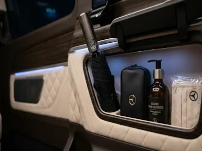 Luxury amenities in a Mercedes V-Class chauffeur hire including a professional umbrella and hygiene kit for executive client protection.