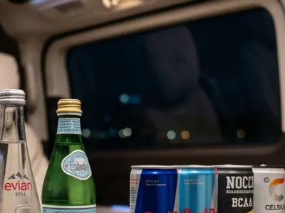 Executive refreshments inside a Mercedes V-Class chauffeur vehicle including premium bottled water and energy drinks for group travel in London.