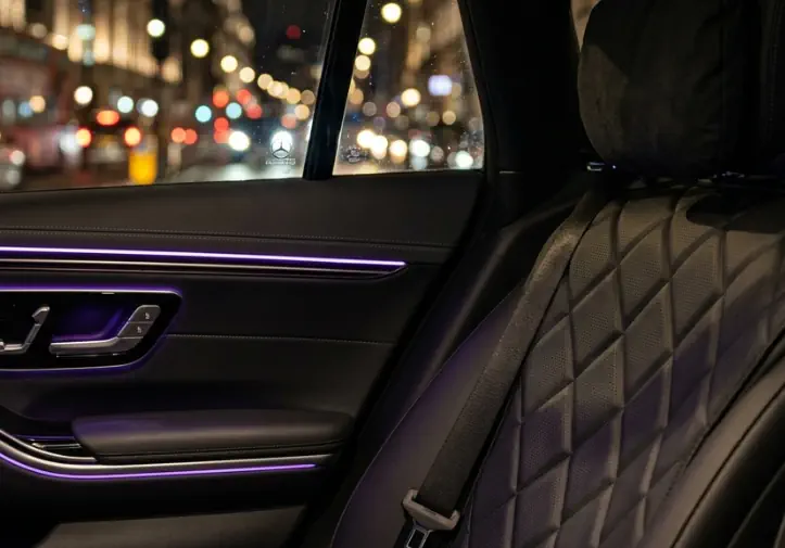 The silent sanctuary of a luxury car interior with ambient lighting, showcasing the professional conduct of an expert chauffeur in London.